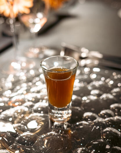 Clear amber herbal broth served warm in a small glass.