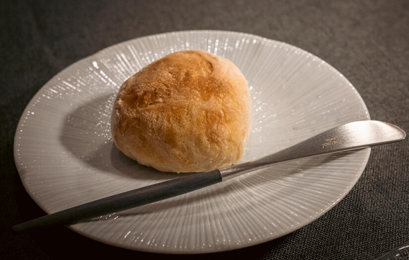 Freshly baked house bread served on a white plate at the Atelier table.
