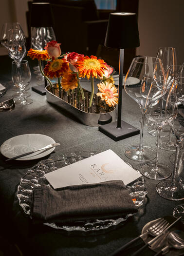 Intimate KARA Atelier table setting with flowers, glassware, ceramic plates and a printed menu.